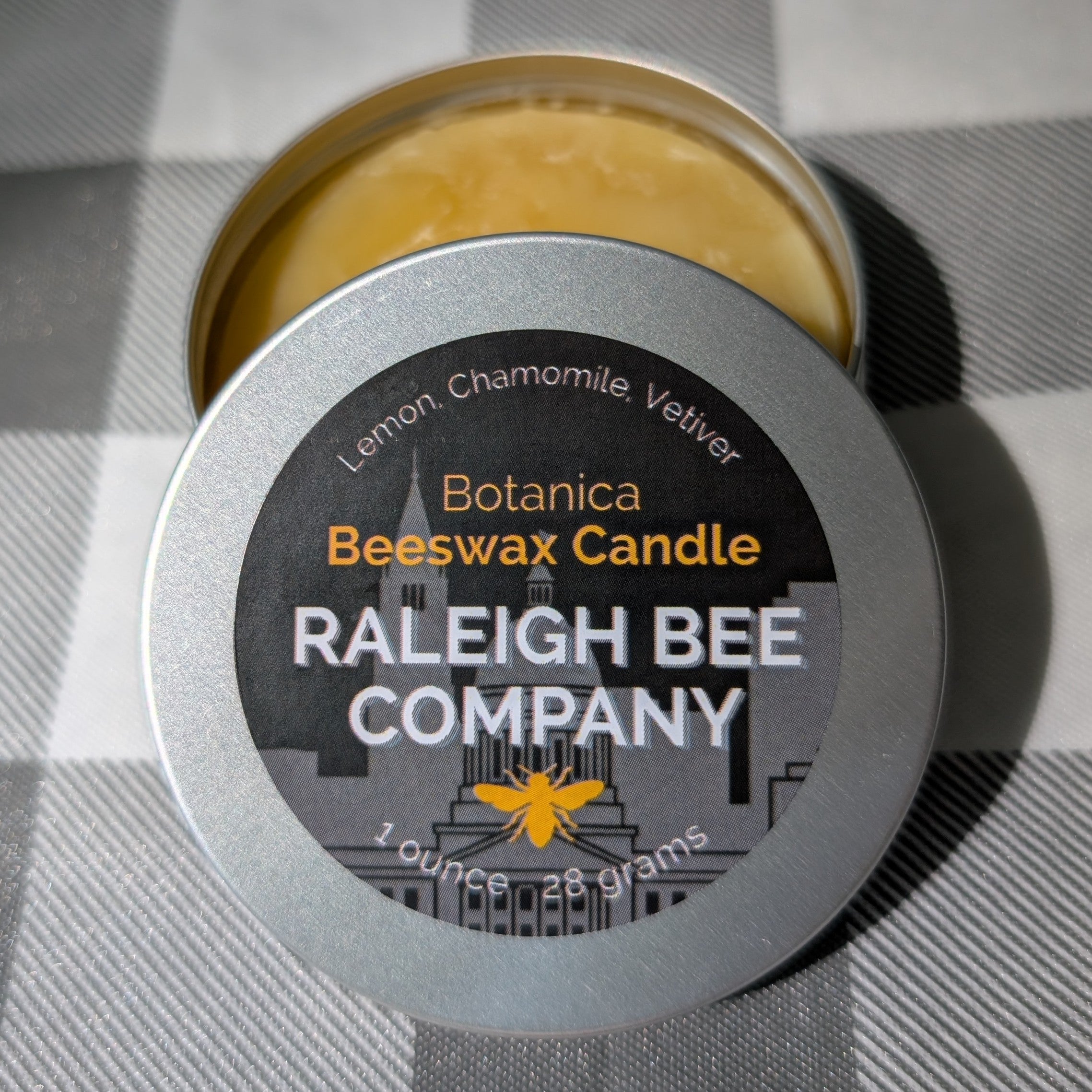 Raleigh Bee Company beeswax candle in a small round tin with 'Botanica' label. Consists of Lemon, Chamomile, and Vetiver.