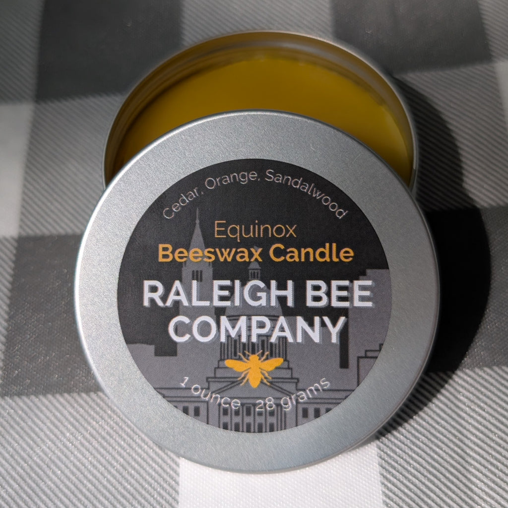 Raleigh Bee Company beeswax candle in a small round tin with 'Equinox' label. Consists of Cedar, Orange, and Sandalwood.