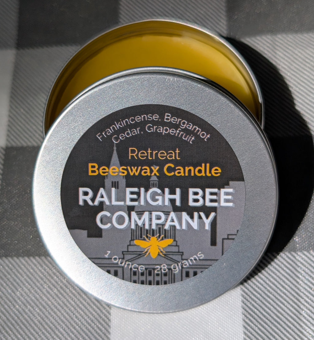 Raleigh Bee Company beeswax candle in a small round tin with 'Retreat' label. Consists of Frankincense, Bergamot, Cedar, and Grapefruit.