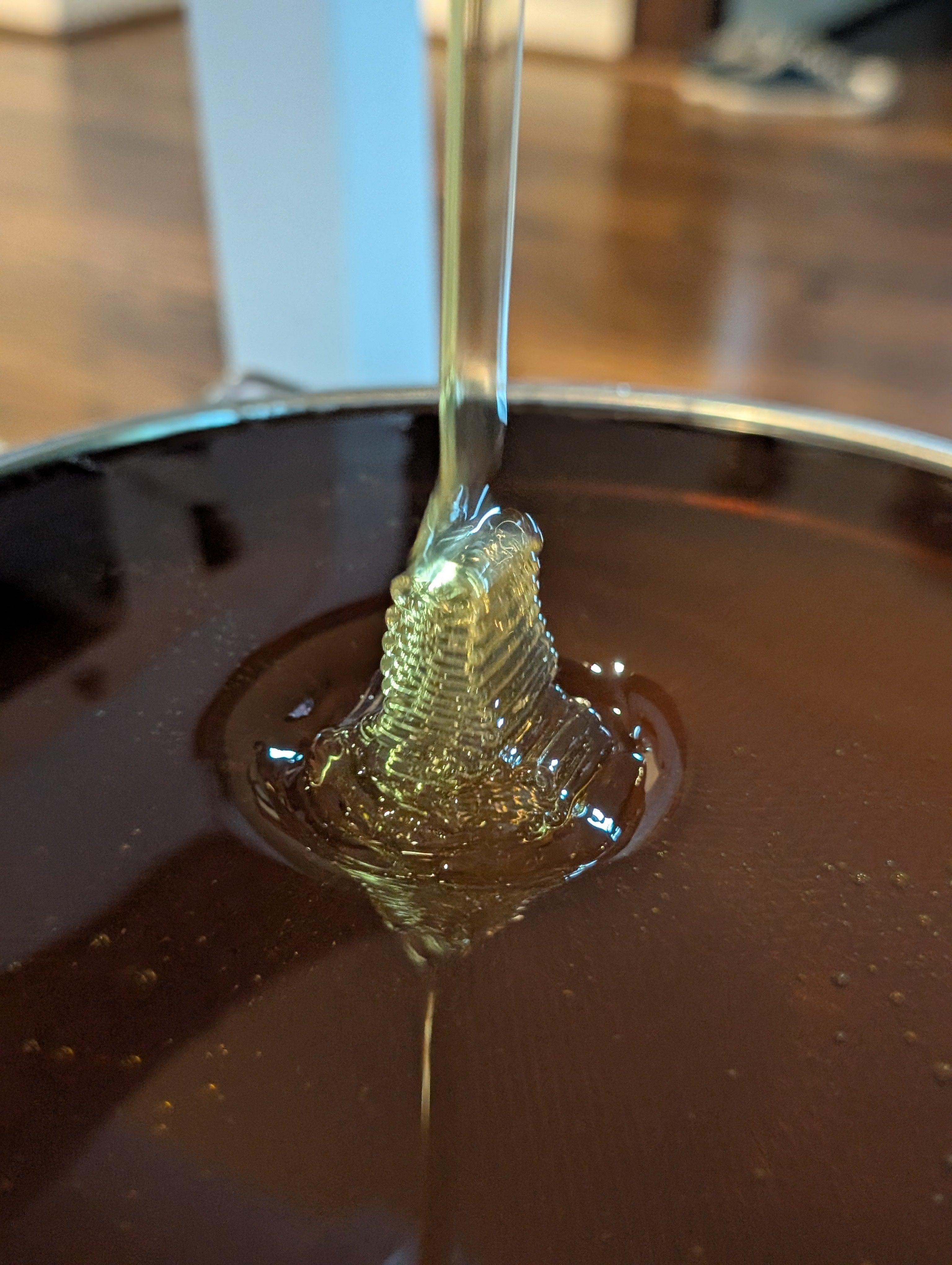 Honey being poured from an extractor into a metal filter.