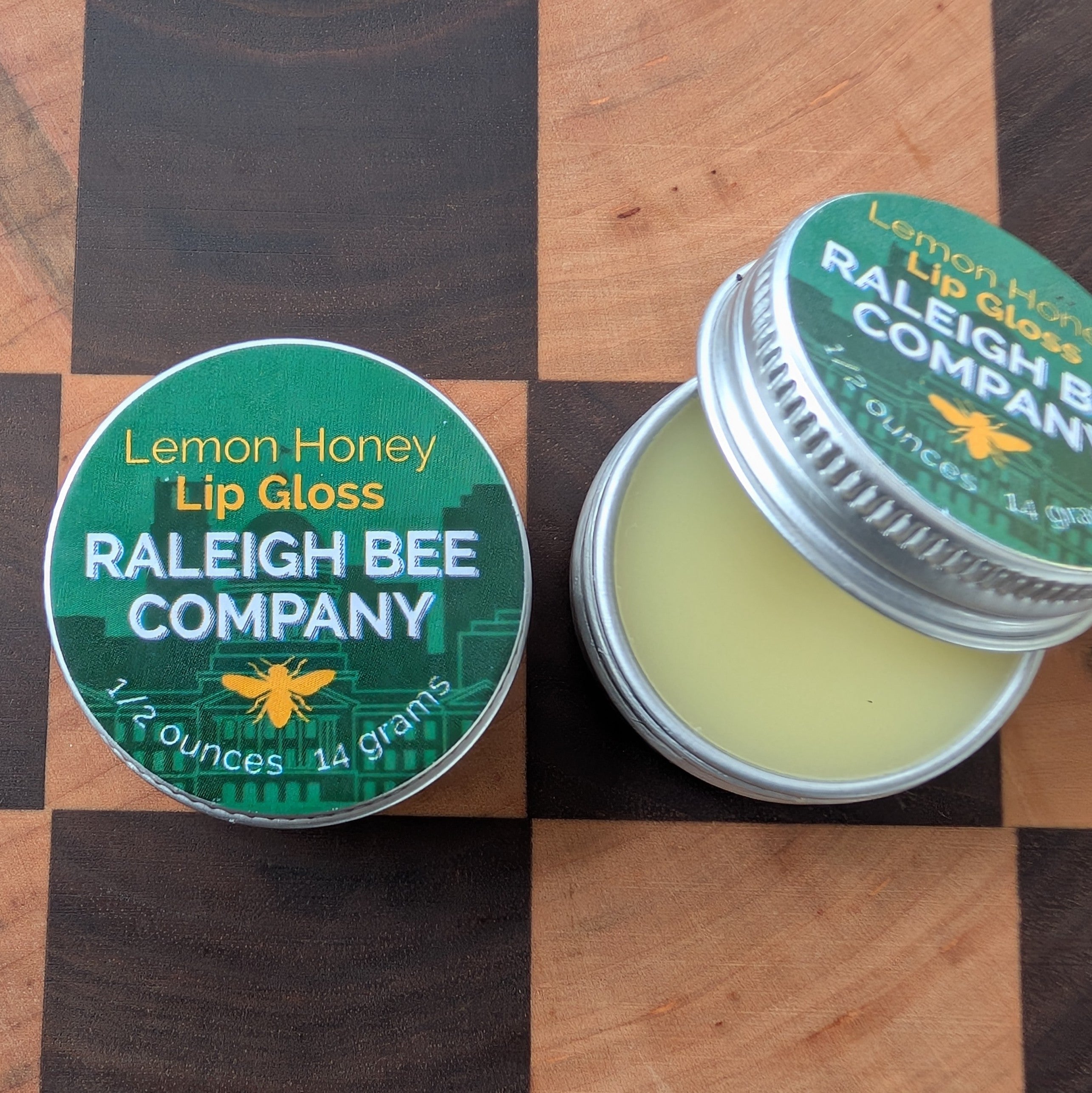 Lemon Honey Lip Gloss from Raleigh Bee Company on a checkered wooden surface