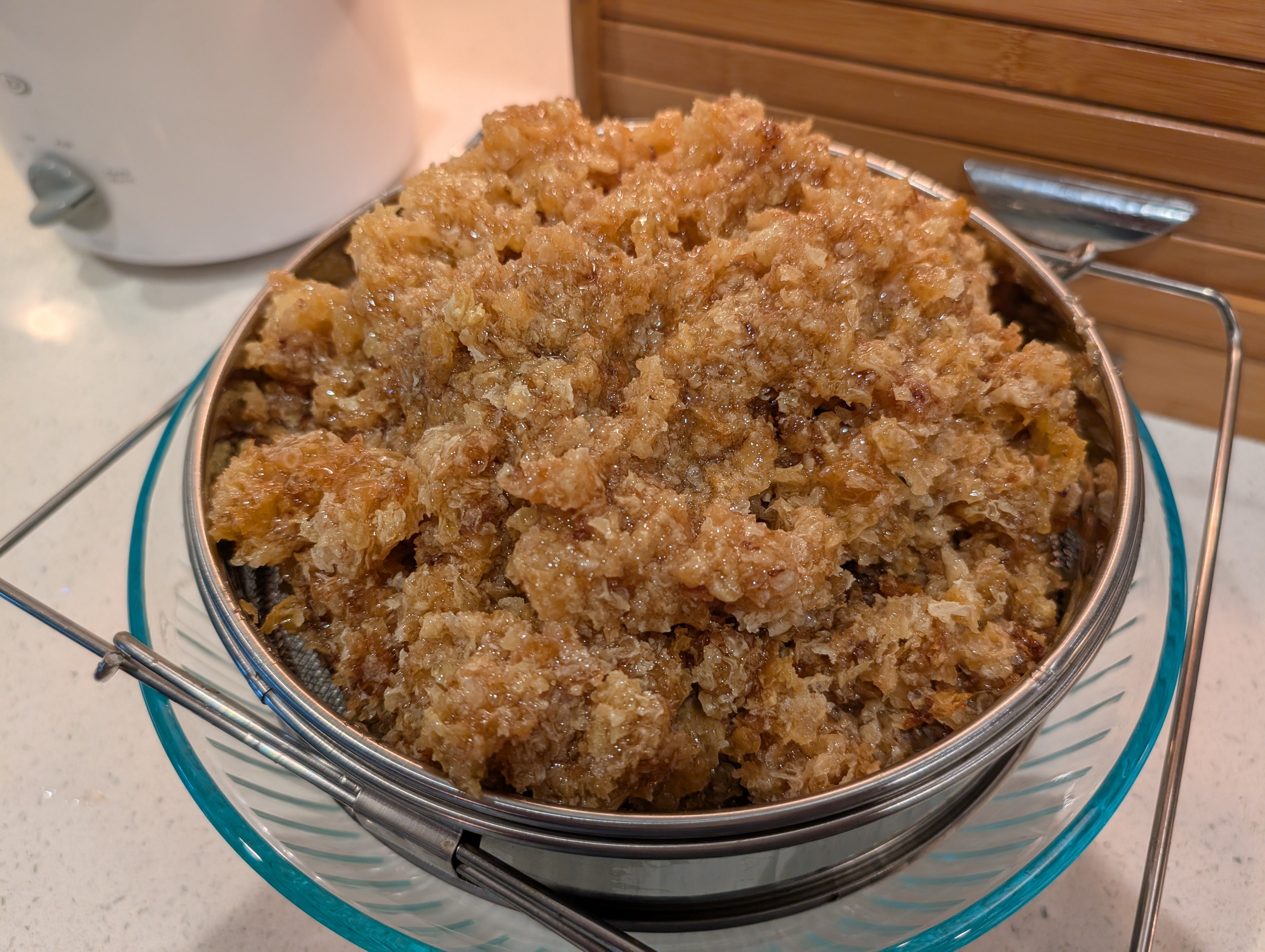 Beeswax in a metal strainer to allow honey to drip into bowl.